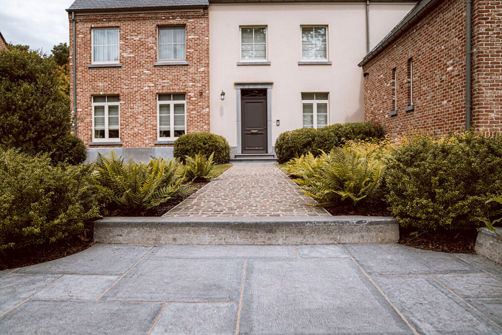 De combinatie van natuurlijke materialen versterkt de Landelijke | Klassieke tuin te Mol. Prachtig aangelegde kasseien, Belgische natuurboordsteen, Belgische natuursteen terrastegels in Romeins verband.